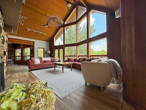 Great room with plenty of seating, a fireplace, and large TV overlooking the private lake