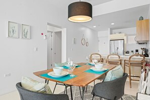 Beautifully designed open space combining dining and relaxation in style - Enjoy cozy gatherings at the elegant wooden dining table under warm lighting - Unwind in the airy living area with plush seating and a seamless indoor outdoor feel