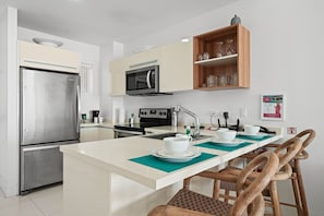 Modern, fully equipped kitchen designed for effortless cooking and dining - Enjoy your morning coffee or evening wine at the stylish breakfast bar - Sleek countertops, stainless steel appliances, and cozy seating make it the perfect spot to gather