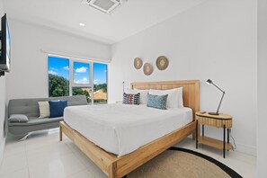 Deep relaxation in this beautifully designed bedroom with a plush king size bed - Breathtaking views & natural light pouring through the large windows - Thoughtfully decorated with warm wood tones, soft linens & stylish accents for a serene escape