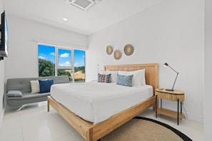 Deep relaxation in this beautifully designed bedroom with a plush king size bed - Breathtaking views & natural light pouring through the large windows - Thoughtfully decorated with warm wood tones, soft linens & stylish accents for a serene escape