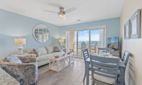 View of living room, dining table, and oceanfront views
