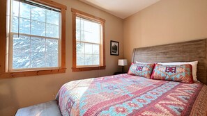Bedroom: patterned bed, windows. Cozy space.
