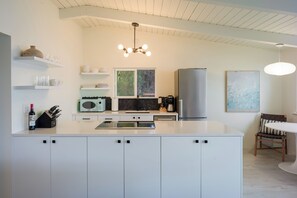 An immaculate, chef-inspired kitchen is fully stocked with high-end appliances and all the cookware and bakeware needed to create gourmet, unforgettable meals, all while enjoying stunning sunsets and breathtaking views.