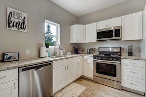 The fully equipped kitchen features modern appliances, a gas range, a dishwasher, and a coffee station with complimentary coffee and spices.





