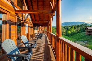The sun begins to dip below the horizon, casting long shadows across the house and illuminating the breathtaking views of the surrounding landscape