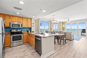 Cook, dine, and relax in this open-concept kitchen and living area, where floor-to-ceiling windows showcase panoramic Gulf views.