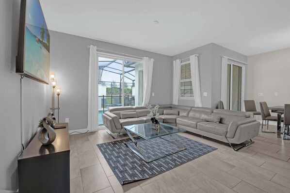 Experience modern comfort in this spacious living room with a stunning view of the pool, perfect for relaxation and family gatherings.