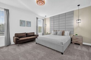 Relax in this spacious bedroom with a plush bed, cozy sofa, and elegant lighting, perfect for a restful stay.
