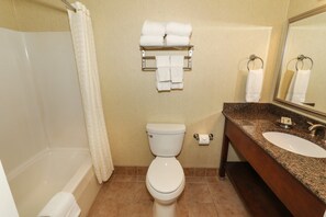 Clean and modern bathroom with a shower/tub combo, granite vanity, and fresh towels.