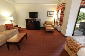 Spacious suite featuring a plush bed, cozy seating area, and natural light from large windows.