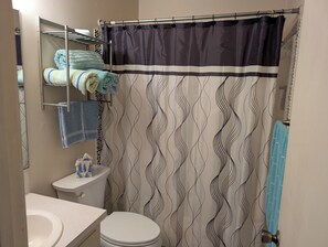 bathtub with shower and towels, shampoo, bath soap.