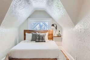 The queen sized bed rests comfortably in a cozy nook