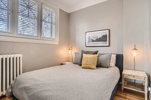 Cozy queen sized bed that is complemented by the rooms high ceilings and natural lighting