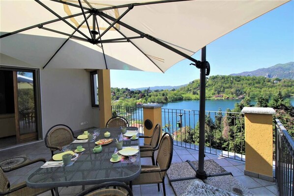 ampia terrazza con vista lago, tavolo esterno e ombrellone 
