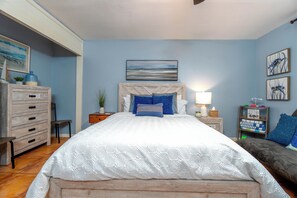 Step into comfort in this cozy bedroom featuring a plush queen bed and a refreshing ceiling fan for those warm nights. Enjoy the serene decor, hardwood floors, and ample storage for a perfect home away from home. Book your stay today! 🛏️✨