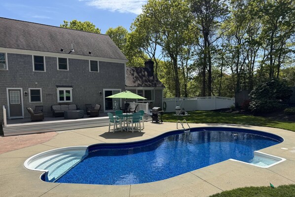 View of the back of the house and in-ground pool with plenty of patio furniture for your whole group