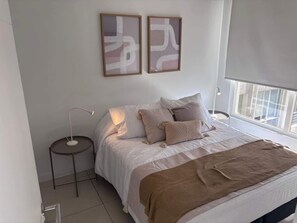 Cozy bedroom with natural light, modern decor, and a comfortable queen-sized bed for a relaxing stay.