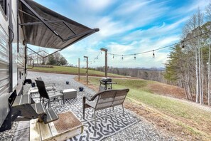 Lounge under the awning with string lights and mountain views all around.