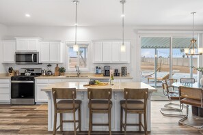The gourmet kitchen features upgraded appliances and a center island table with barstool seating.