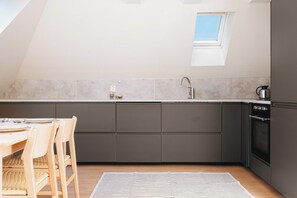 A modern kitchen, bathed in natural light, showcasing sleek dark cabinetry and a touch of airy charm.