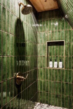 "Relax and unwind in this beautifully designed bathroom, featuring green stacked tile and gold fixtures for a touch of luxury.
