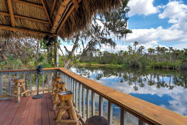 Welcome to Riverside Hut! Where you can relax at the tiki bar with breathtaking waterfront views, the perfect spot to soak in the peaceful surroundings..
