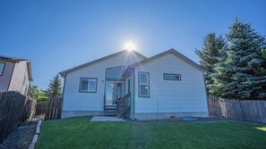 The backyard features a lush lawn, tall trees for added privacy, and a cozy patio space, perfect for enjoying the fresh mountain air.

