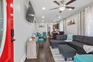 Kick back and relax in the inviting living room, complete with a ceiling fan, large flat-screen TV, plush sectional sofa with an ottoman, and extra upholstered chairs for ultimate comfort.