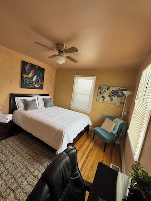 Serene bedroom with queen bed, desk, ceiling fan, and natural light.