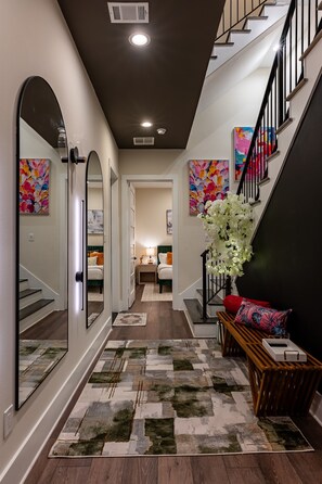 Mirrors, a modern rug, and a touch of tropical flair. This hallway is a vibe. 
