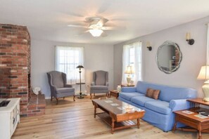 Cozy living room with a brick fireplace, comfy seating, and a TV with streaming services—perfect for unwinding after a day of exploring.