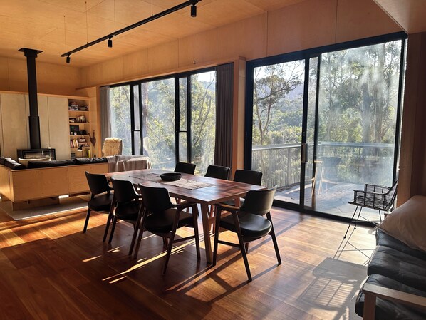 Huge living and dining space with balcony and forest views.