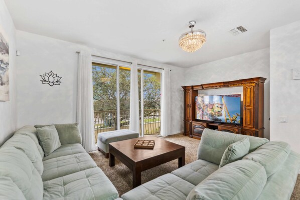 Unwind in a bright and cozy living room with a perfect setup for movie nights - Large windows bring in natural light and offer a peaceful view to enjoy - Stretch out on the plush sectional and catch up on your favorite shows in total comfort