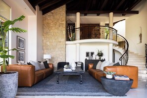 Sink into leather sofas in the main living area, where a vaulted timber cathedral ceiling and a sweeping staircase set the tone for luxury and relaxation.