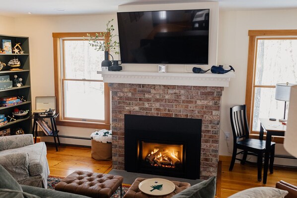 The living room is centered around the charming gas fireplace, featuring a game nook that offers a cozy spot to enjoy board games, puzzles, and books. 