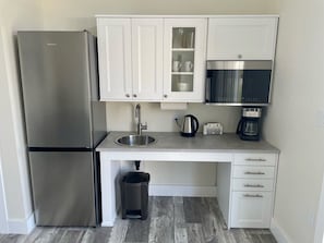 Kitchenette with fridge, sink, microwave and tea/coffee station. There is no stove.
