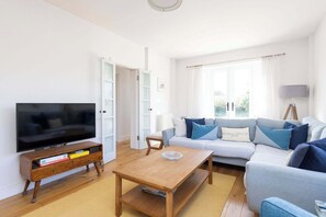 Relax in the cosy lounge of this seaside cottage, featuring a comfortable corner sofa and Smart TV, perfect for unwinding after a day at nearby East Wittering Beach. The inviting living space also includes a log burner for chilly evenings and a sofa 