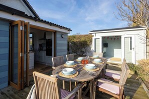 Enjoy outdoor dining on the sunny deck with seating for six, perfect for family meals after a day at the nearby beach. This charming cottage offers a wonderful space for relaxation and making memories.