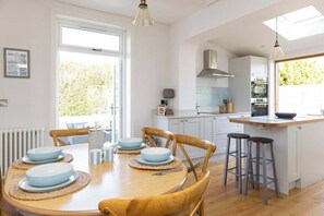 Enjoy family meals and gatherings in the bright and airy open-plan kitchen and dining area, perfect for relaxing after a day at the nearby beach. This inviting space features a dining table with seating for six and seamless access to the outdoor pati