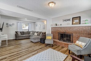 This inviting living space features a charming brick fireplace, plush seating, and a spacious sectional for ultimate comfort. Perfect for cozy nights in or gathering with friends and family.





