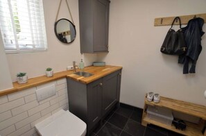 Downstairs cloak room with toilet/sink, washer dryer, coat & shoe rack.