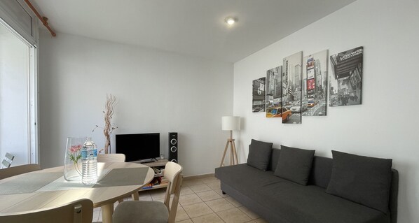 Bright and modern living-dining room with sofa and TV.