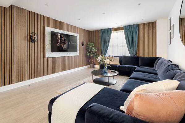 Spacious A/C lounge with wood panels, open kitchen & garden for cosy stays.
