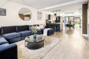 Spacious A/C lounge with wood panels, open kitchen & garden for cosy stays.