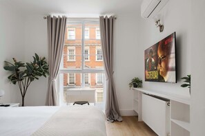 Elegant bedroom with king bed, 50" TV, A/C & dresser – style meets comfort.
