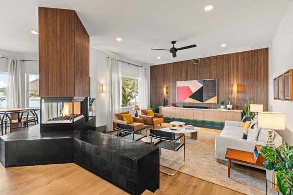 Linger in the walnut-paneled lounge with 85" TV, Sonos Arc Soundbar, cozy gas fireplace and beautiful views of the lake and pool.