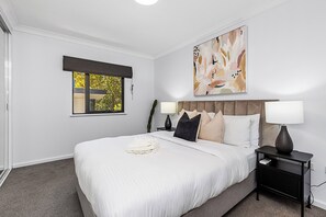 Unwind in a comfortable bedroom, featuring plush bedding, contemporary décor, and ample natural light.