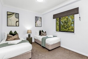 Rest comfortably in a well-lit twin bedroom, offering a peaceful retreat with a pleasant window view.