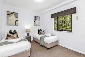 Rest comfortably in a well-lit twin bedroom, offering a peaceful retreat with a pleasant window view.